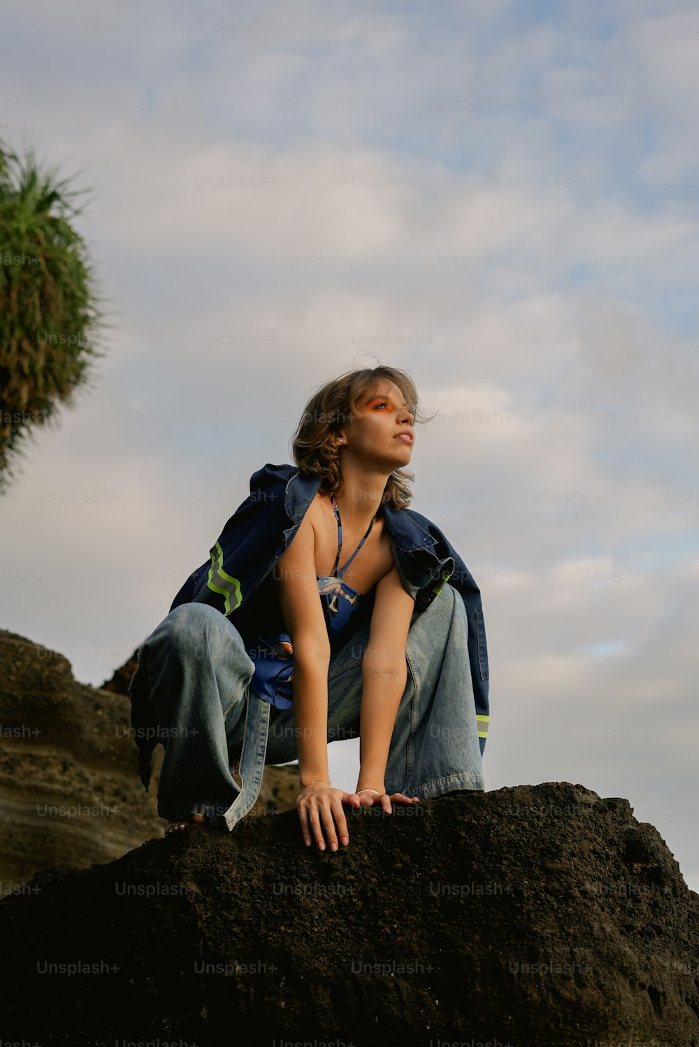 a woman sitting on top of a large rock