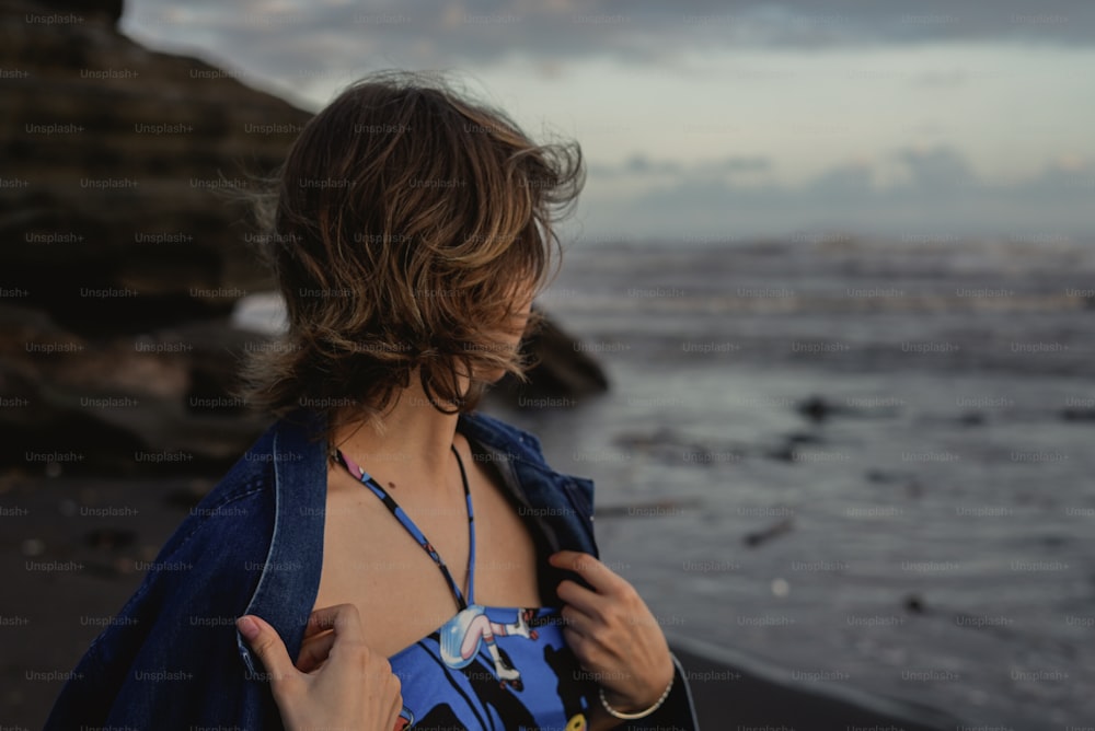 a woman standing on a beach next to the ocean