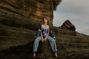 a woman sitting on top of a rock next to a cliff