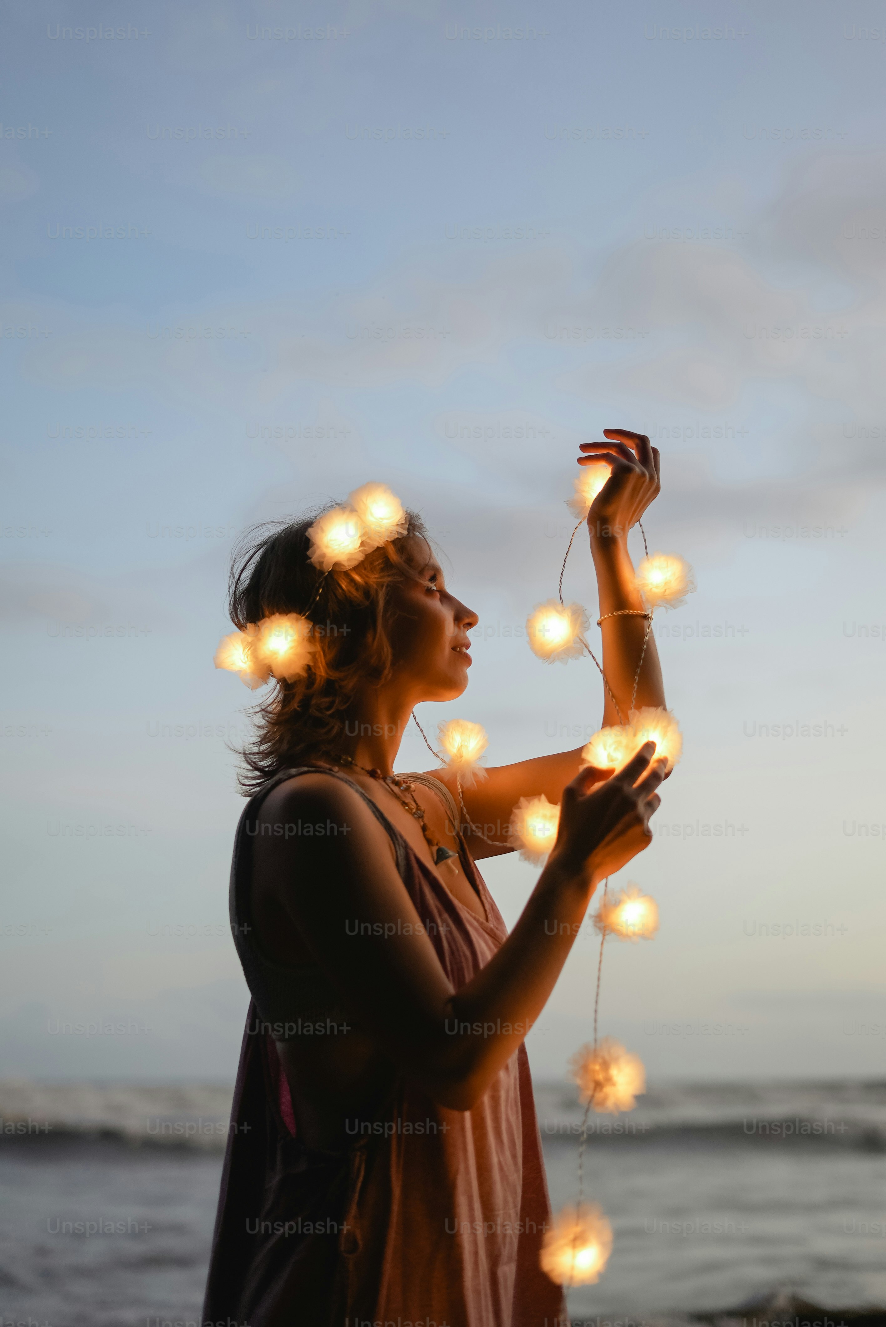 a woman standing on a beach holding a string of lights