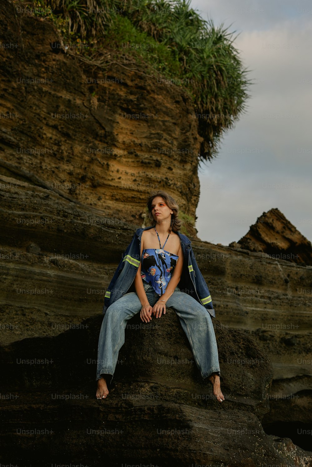 Una mujer sentada en la cima de una roca junto a un acantilado