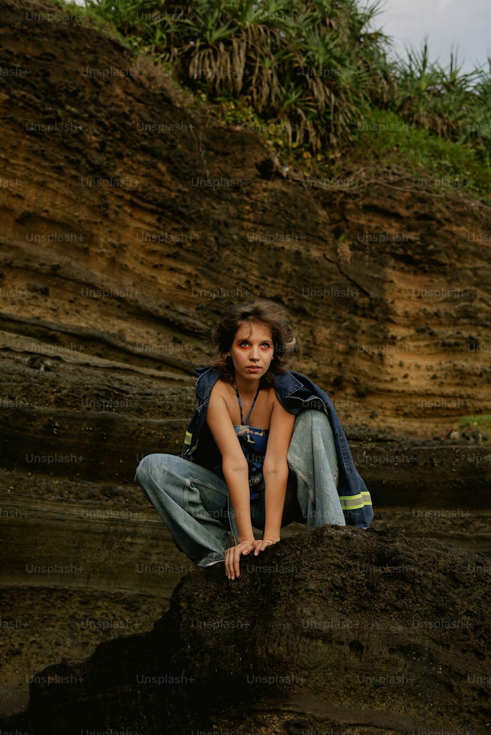 a young girl is sitting on a rock