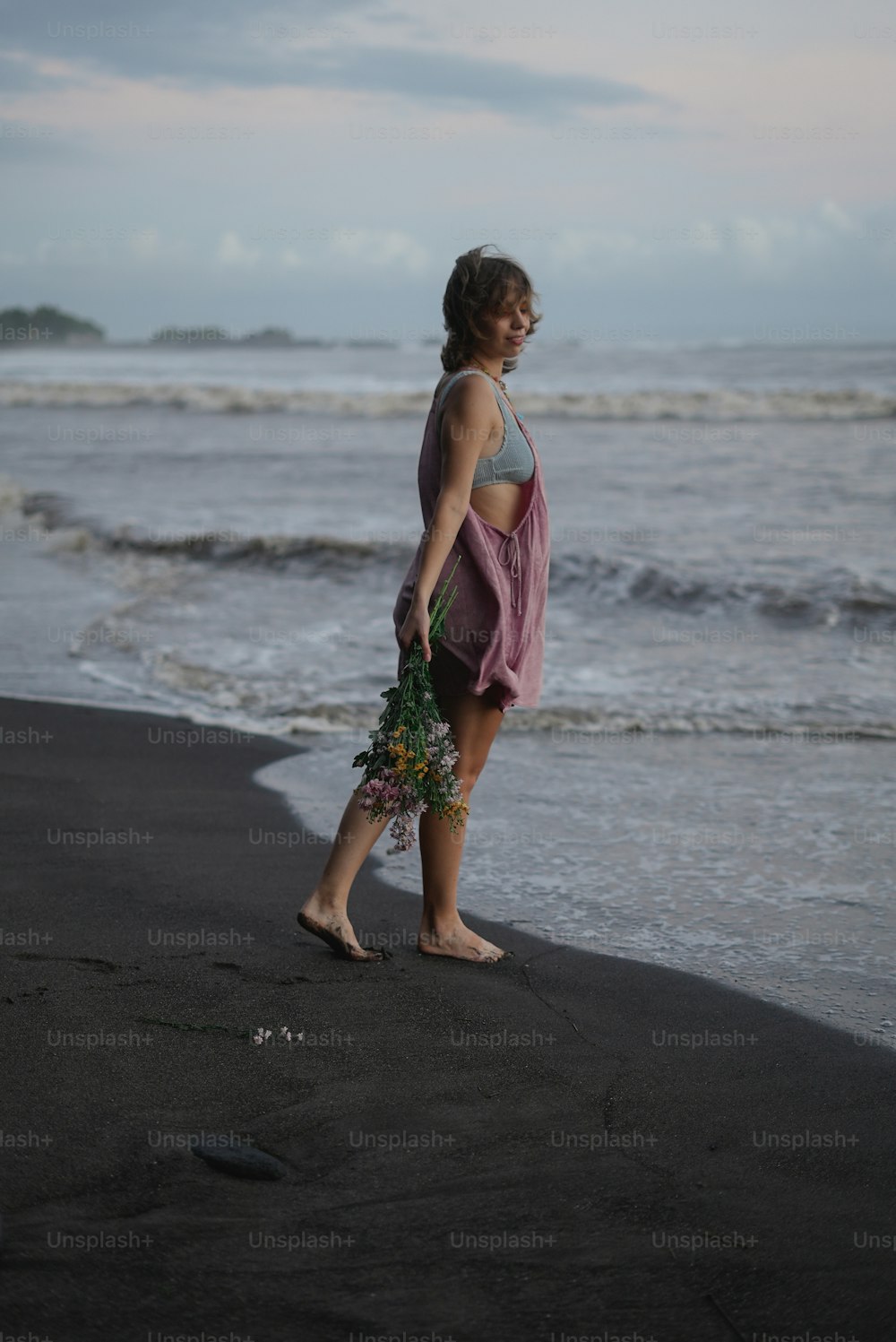 a woman standing on a beach next to the ocean