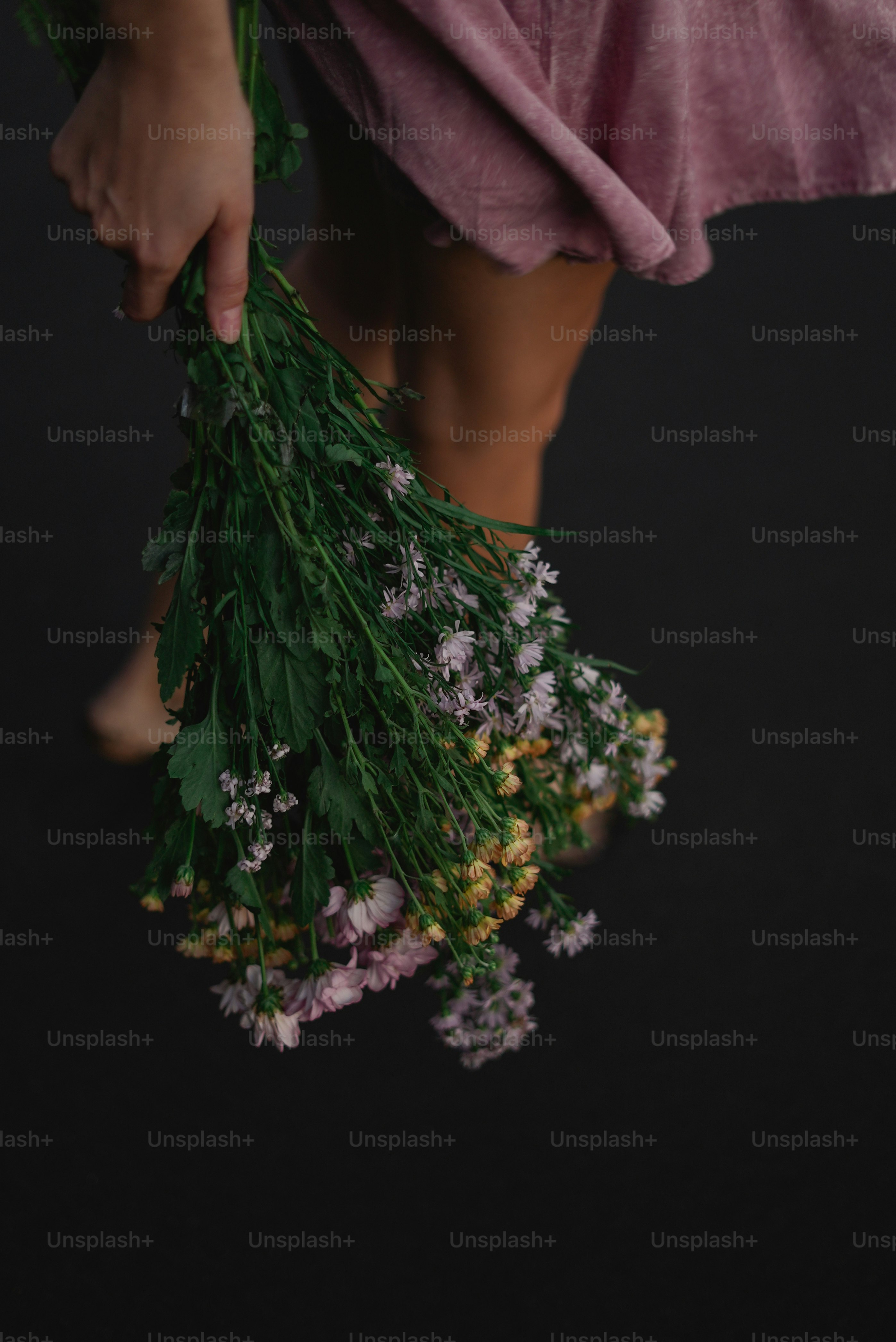 a person holding a bunch of flowers on a black background
