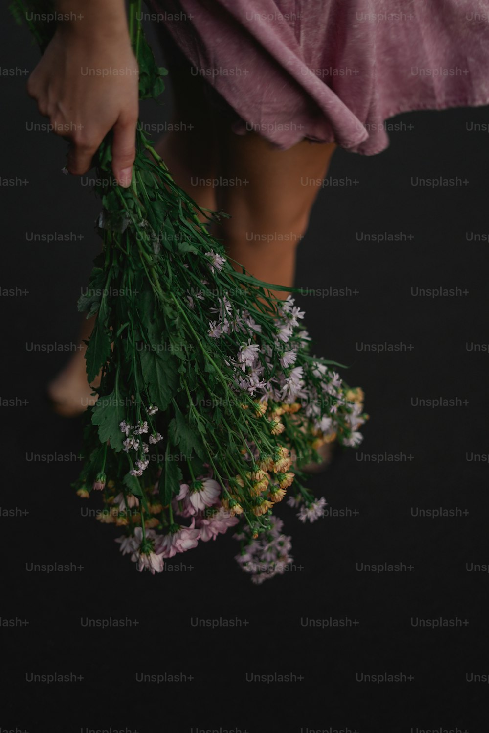 una persona che tiene un mazzo di fiori su uno sfondo nero