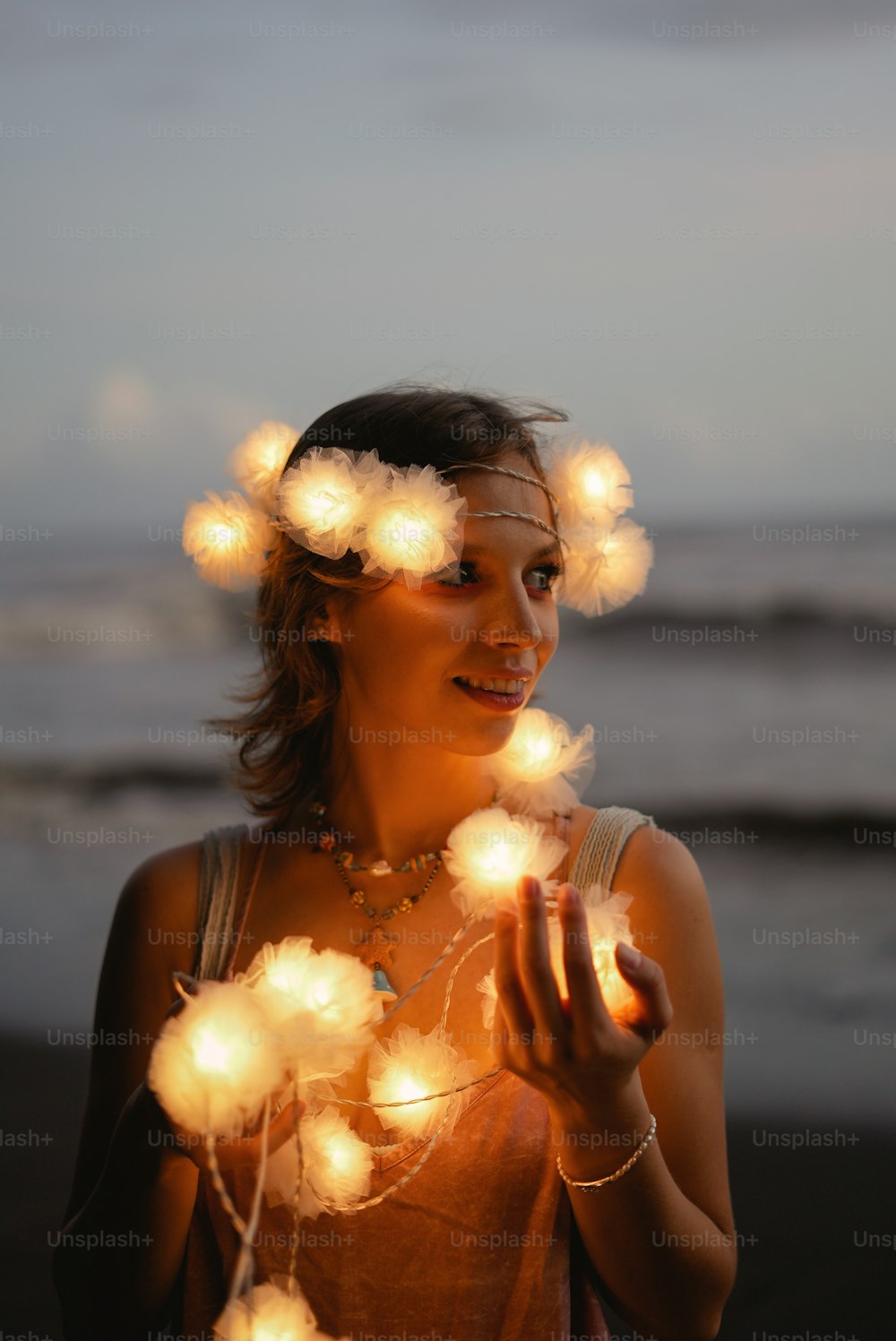 해변에 서 있는 한 여자가 불빛의 끈을 들고 있다