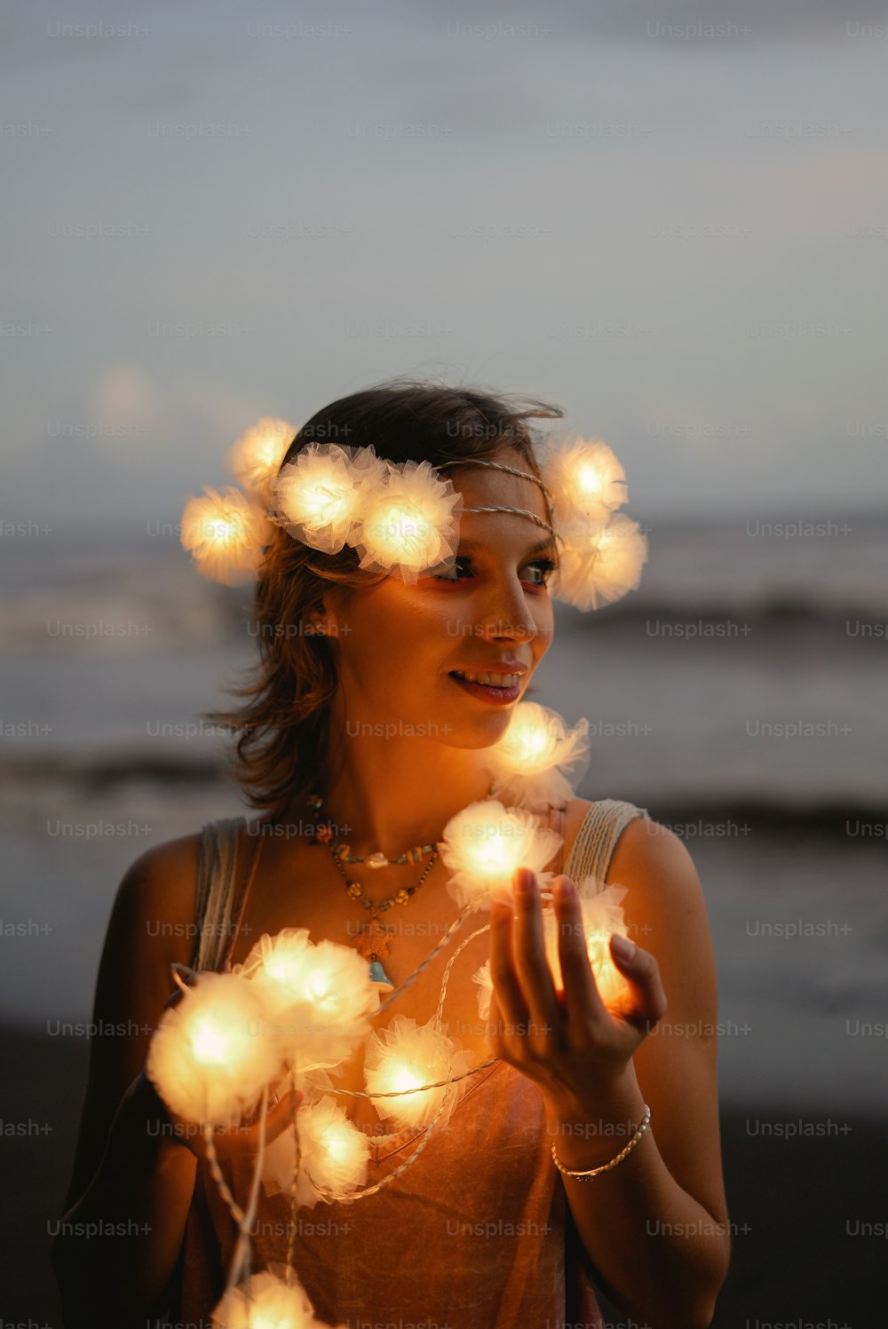 a woman standing on a beach holding a string of lights