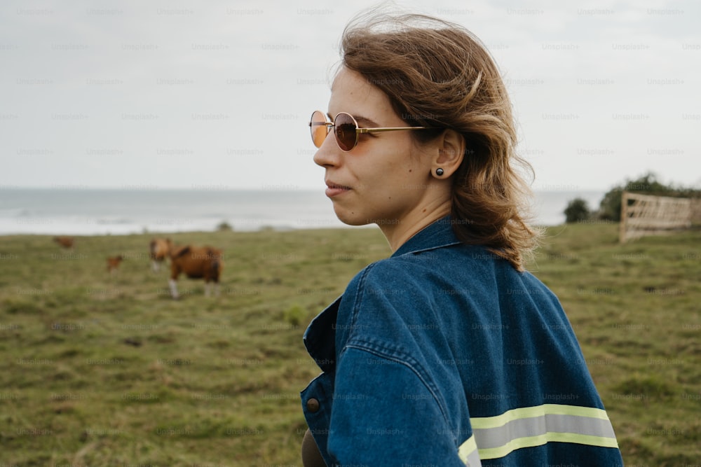 a woman standing in a field with cows in the background