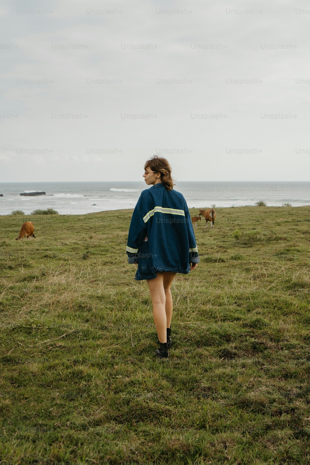 a woman in a blue dress walking across a field