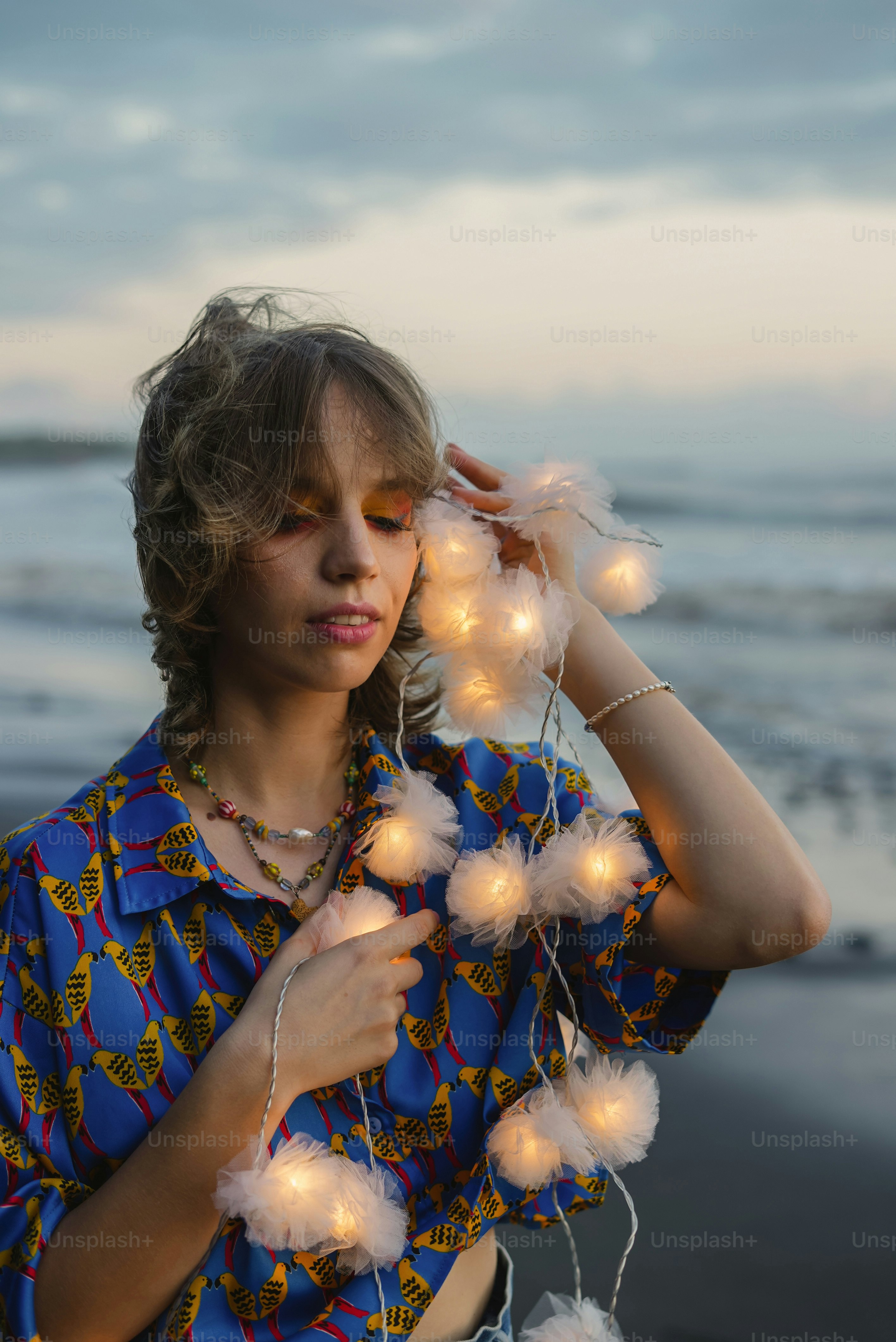 a woman standing on a beach holding a string of lights