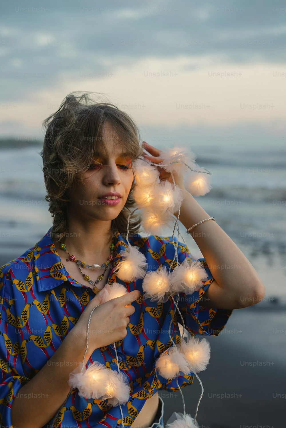 a woman standing on a beach holding a string of lights
