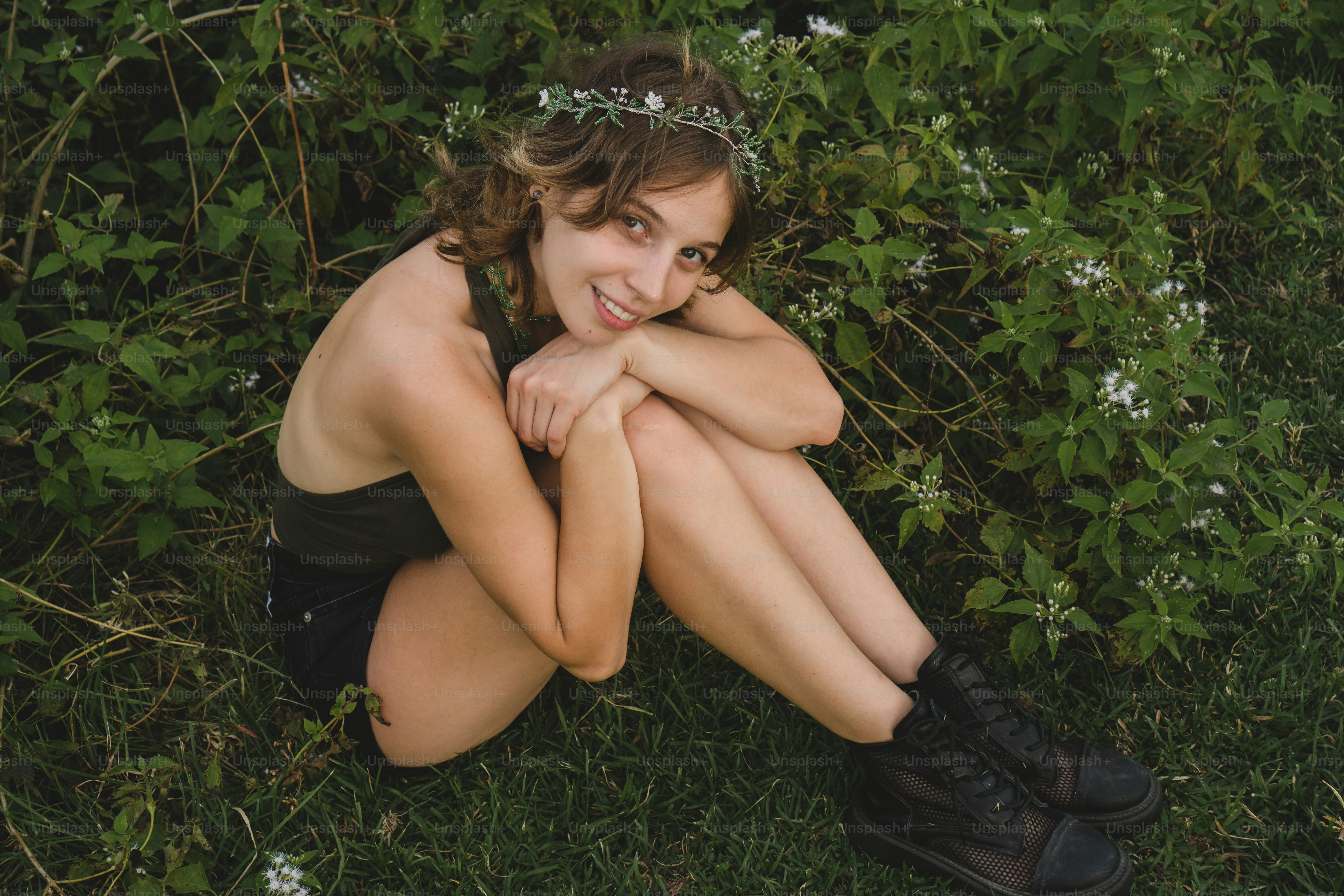 a woman sitting in the grass with her arms crossed