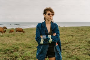 a woman standing in a field with cows in the background