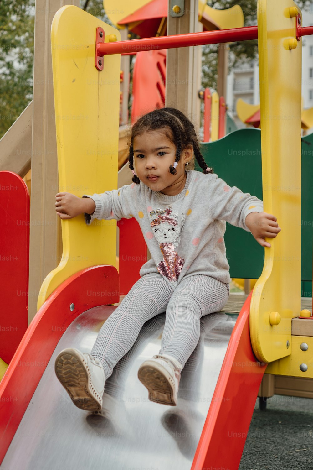 a little girl sitting on a slide at a playground