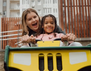 a woman and a little girl riding on a toy car