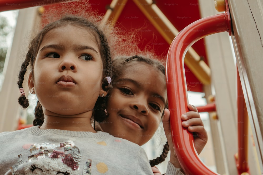 two little girls standing next to each other on a playground