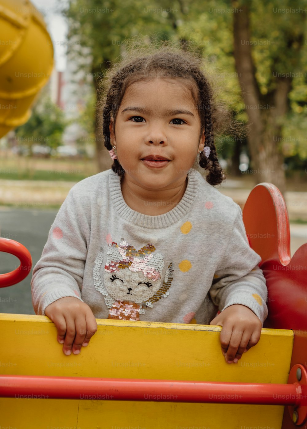 a little girl sitting in a yellow toy car