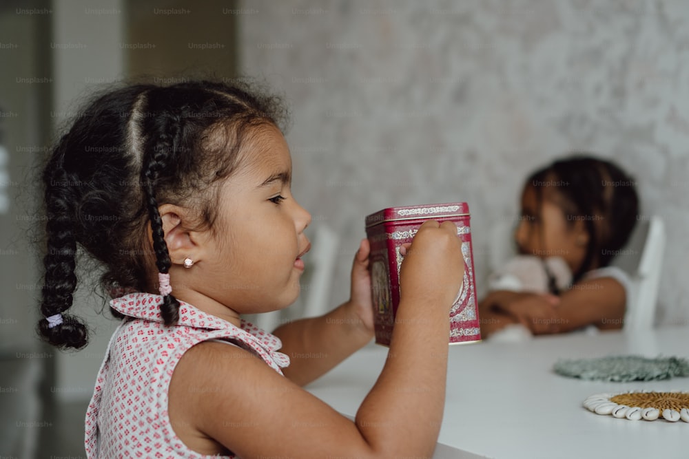 a little girl holding a can of food at a table