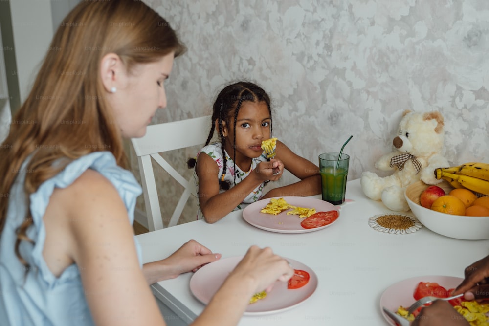 Un grupo de niños sentados en una mesa comiendo alimentos