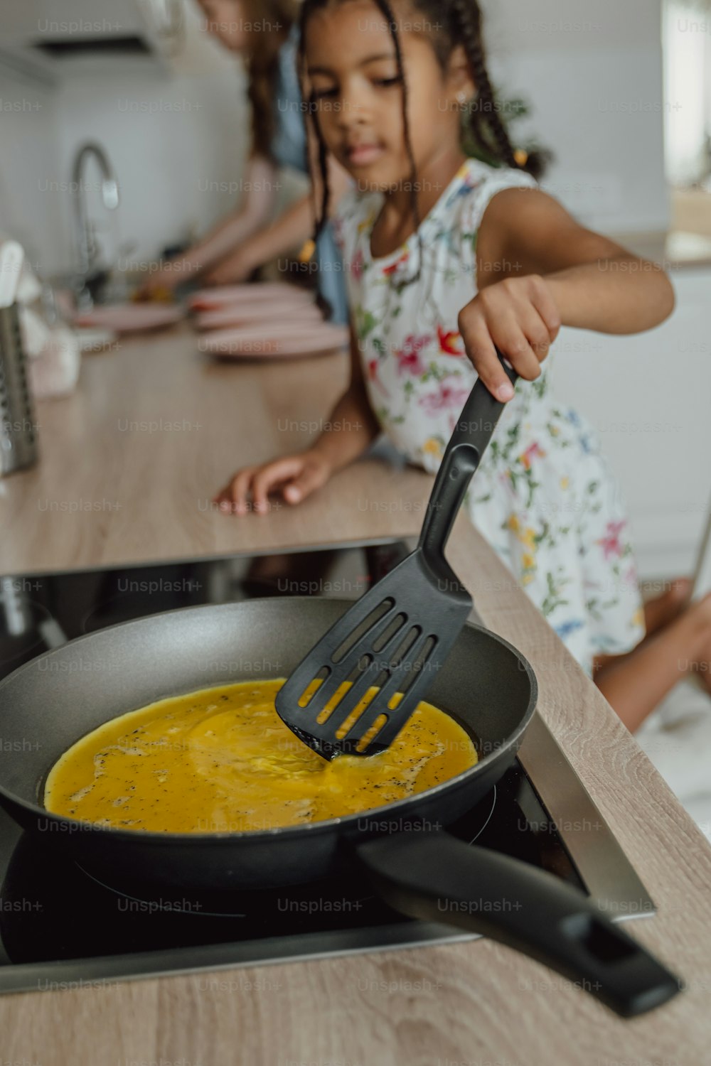 a little girl stirring a pan of food on a stove