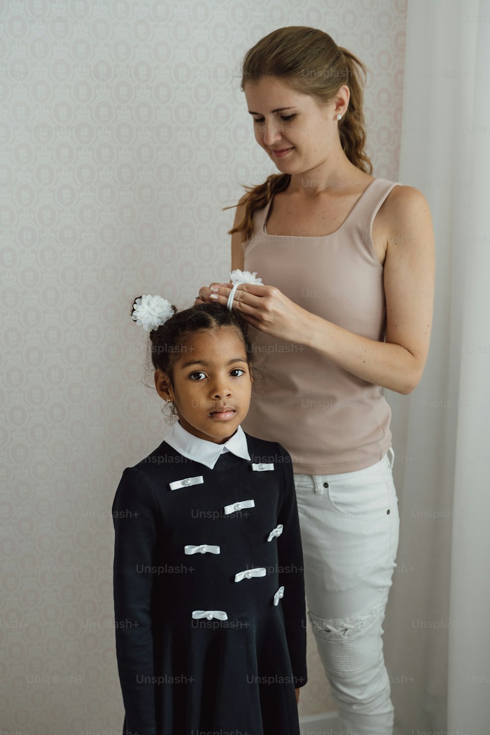 a woman combing a young girl's hair in a room