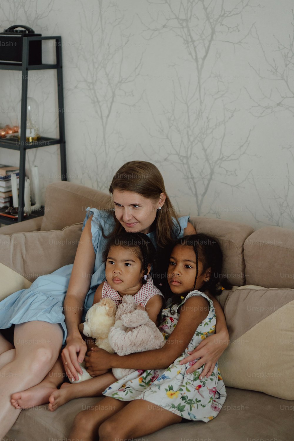 Eine Frau, die mit zwei Kindern auf einer Couch sitzt