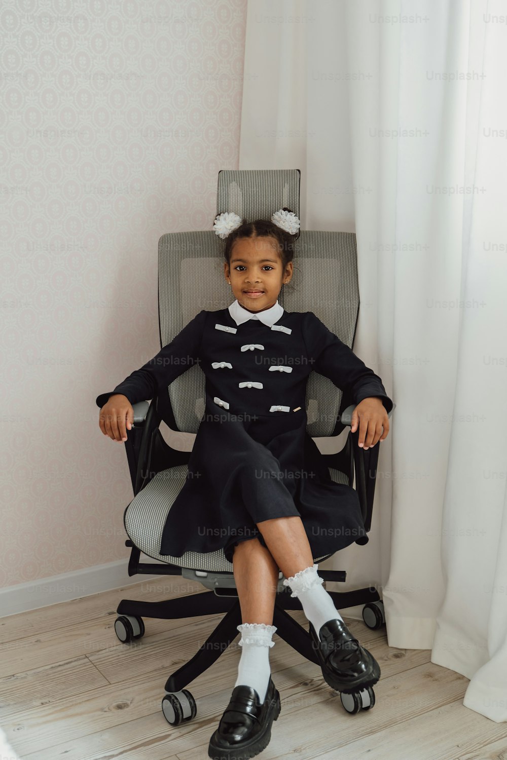 a little girl sitting in a chair with her hair in a bun