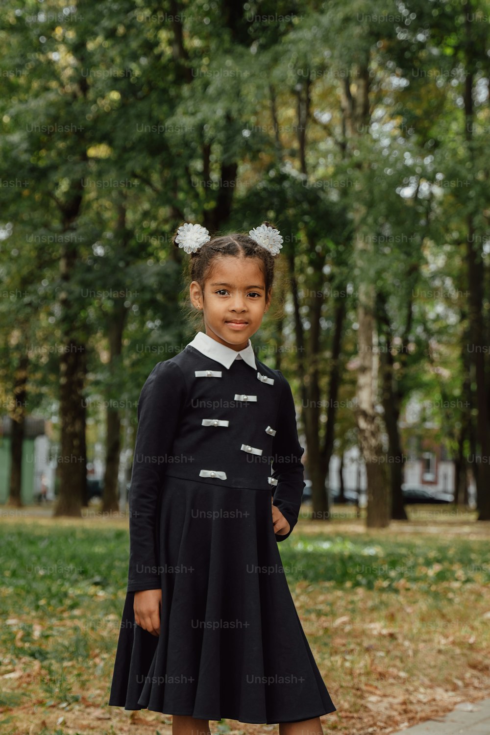 Ein junges Mädchen in einem schwarzen Kleid, das auf einem Bürgersteig steht