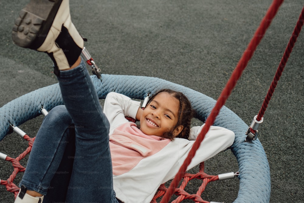 a little girl sitting in a swing with her feet up