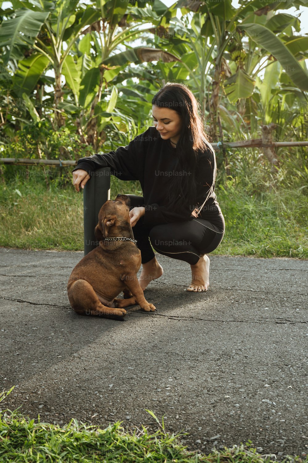 a woman kneeling down next to a brown dog