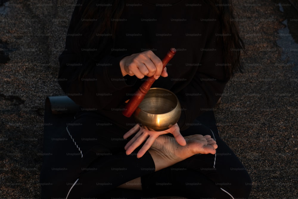 a person holding a bowl and a wooden stick