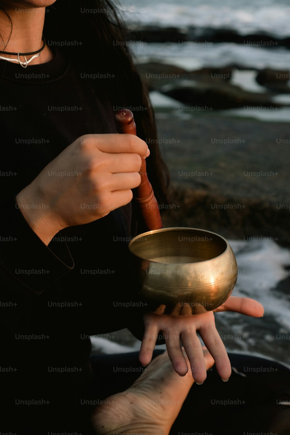 a woman holding a gold singing bowl in her hands