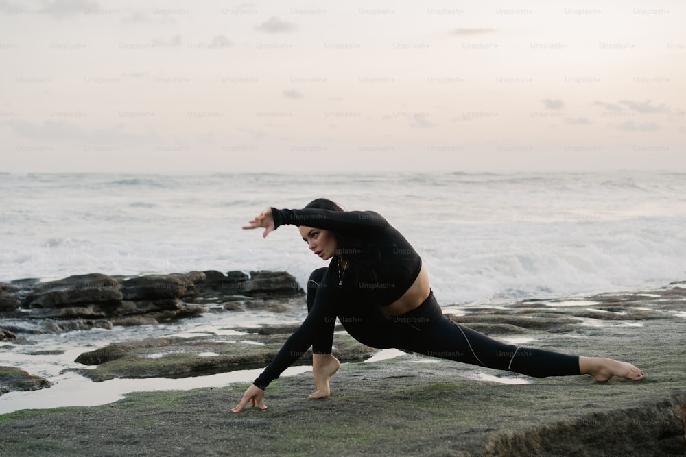 Una mujer haciendo una pose de yoga en la playa