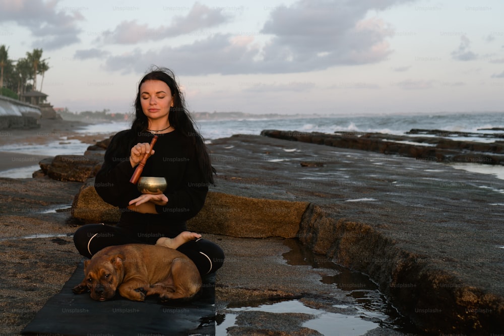 Eine Frau, die neben einem Hund auf einem Felsen sitzt