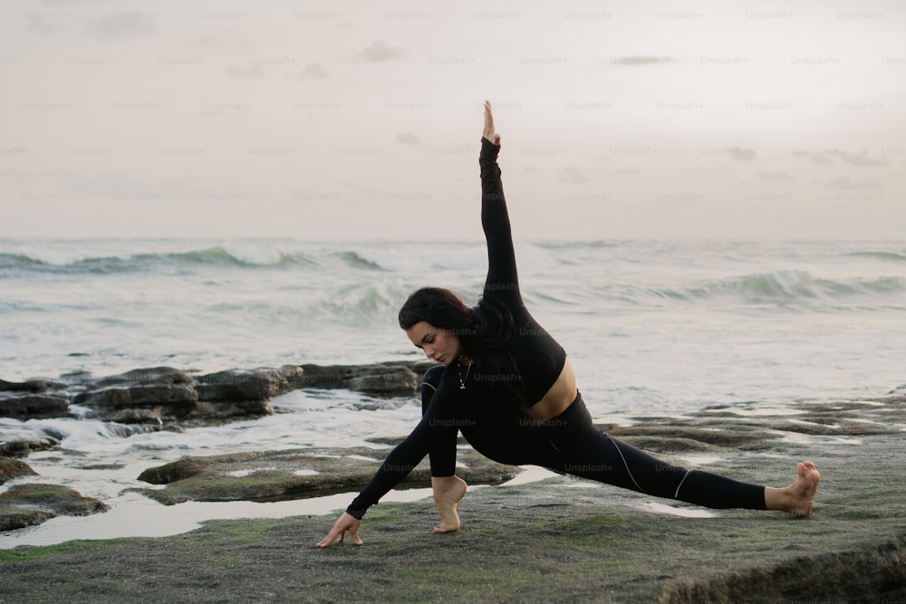 Una donna che fa una posa yoga sulla spiaggia