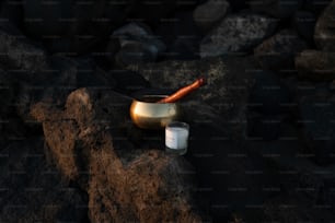 a candle and a bowl sitting on some rocks