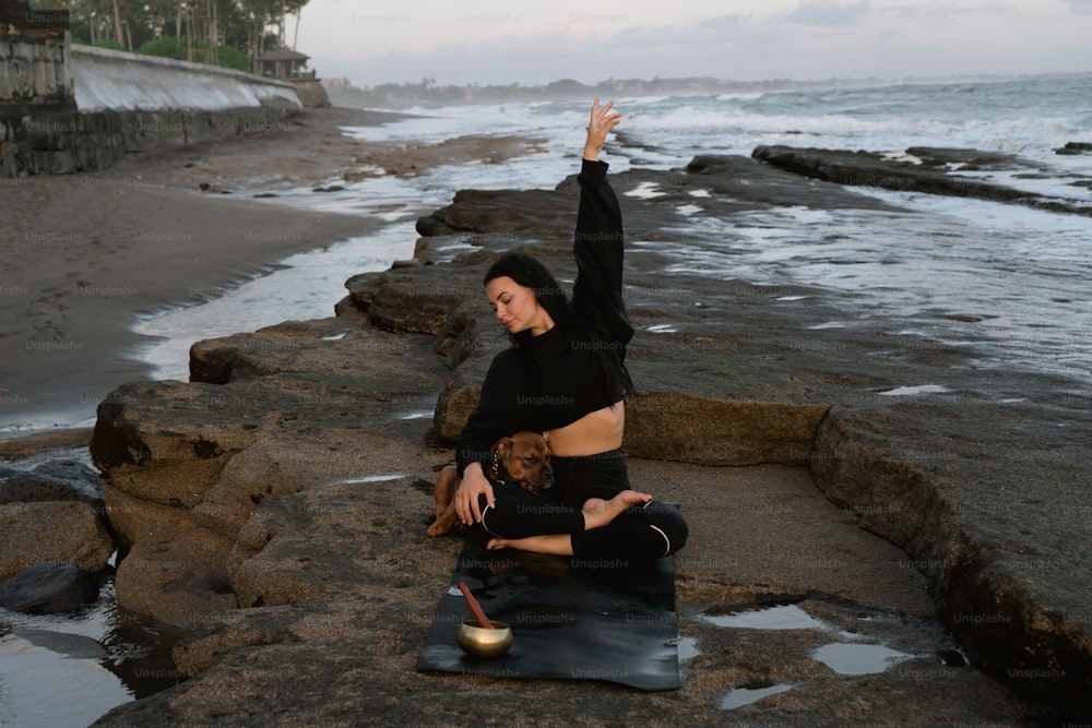 uma mulher sentada em uma rocha perto do oceano