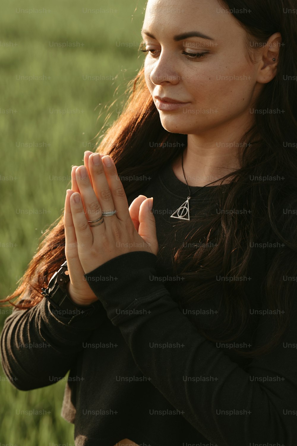 a woman standing in a field with her hands together