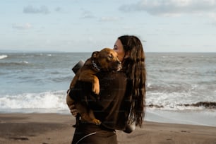 a woman holding a dog on the beach