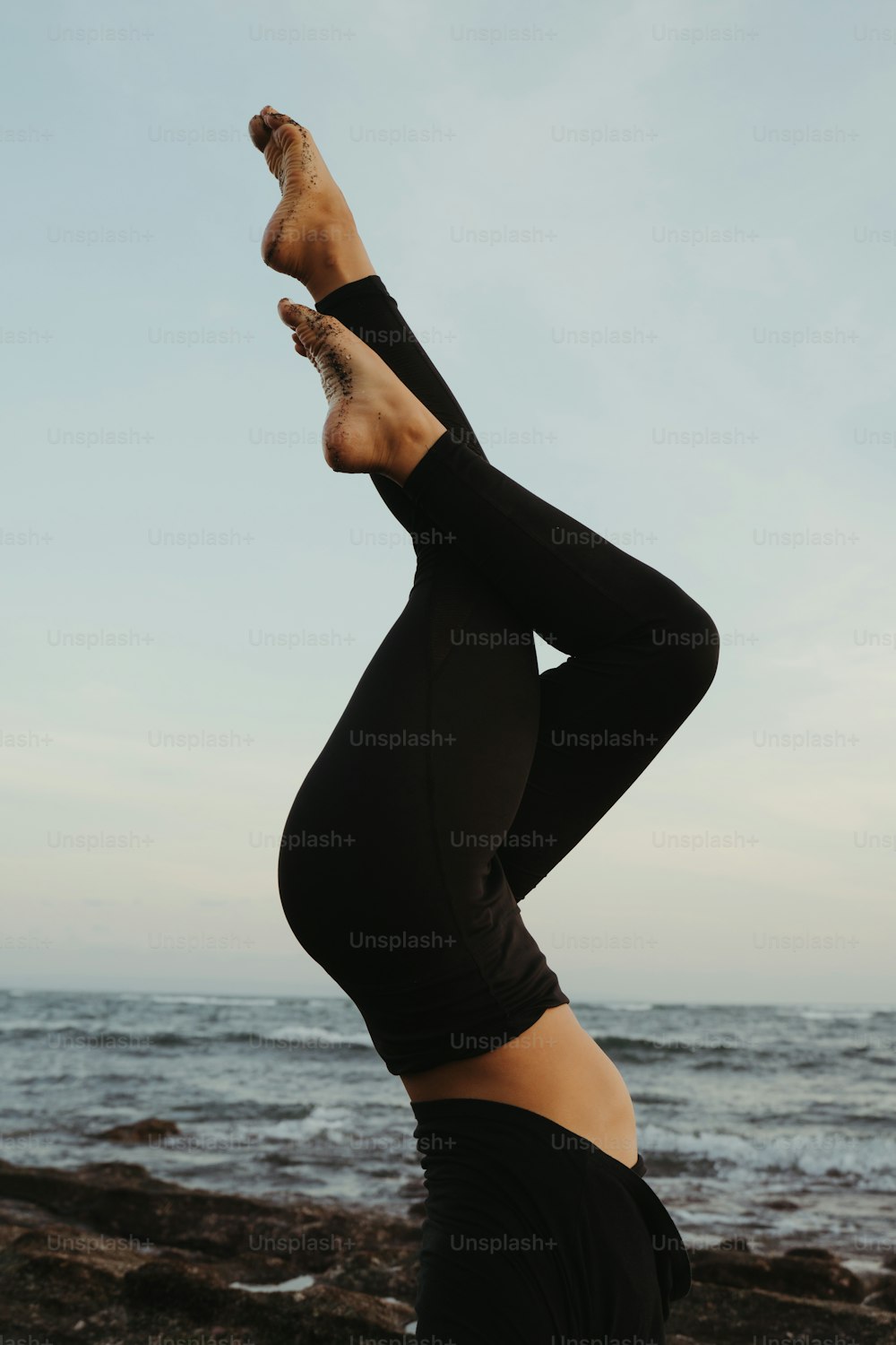Una donna che fa una posa yoga sulla spiaggia