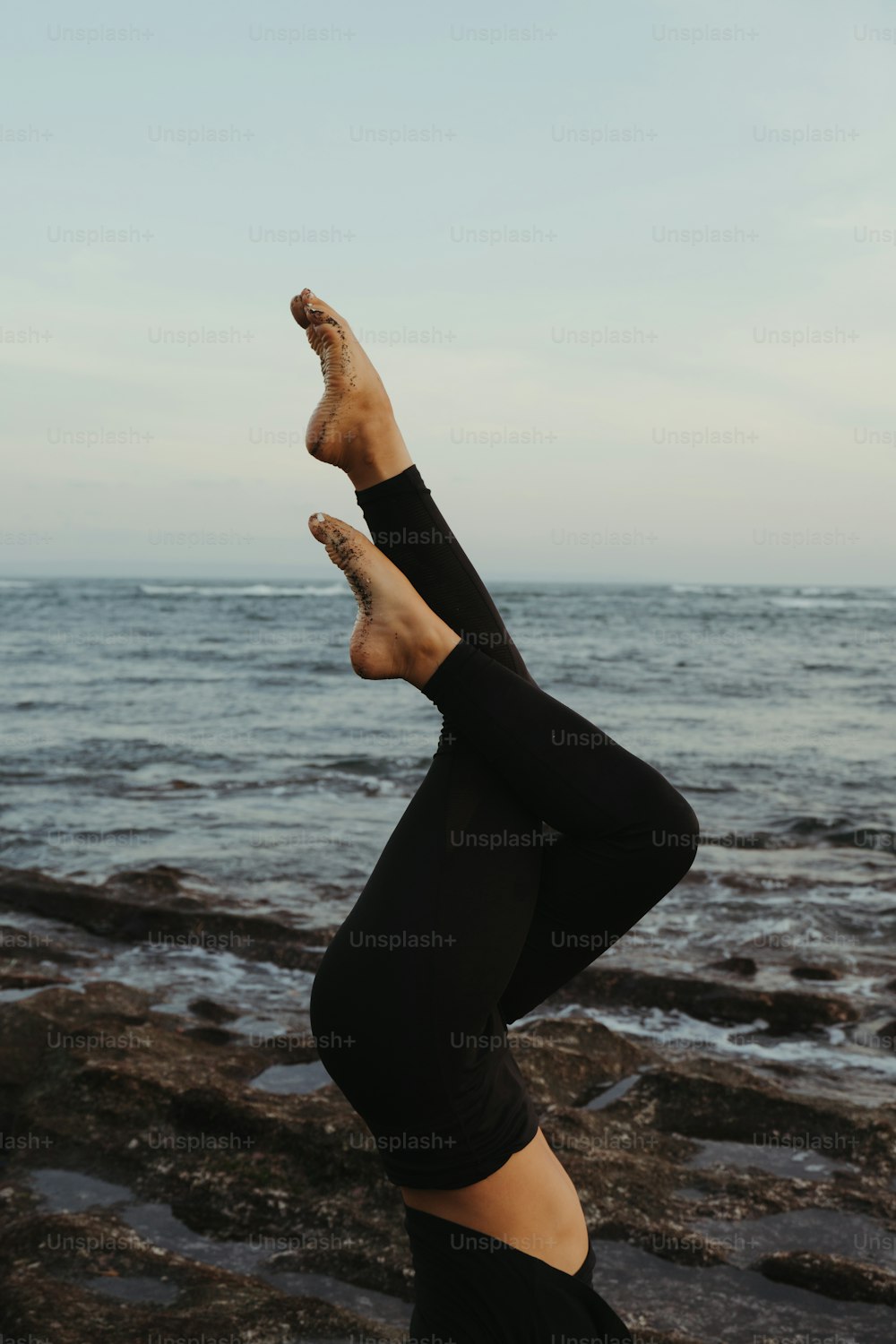 a woman doing a handstand in front of the ocean