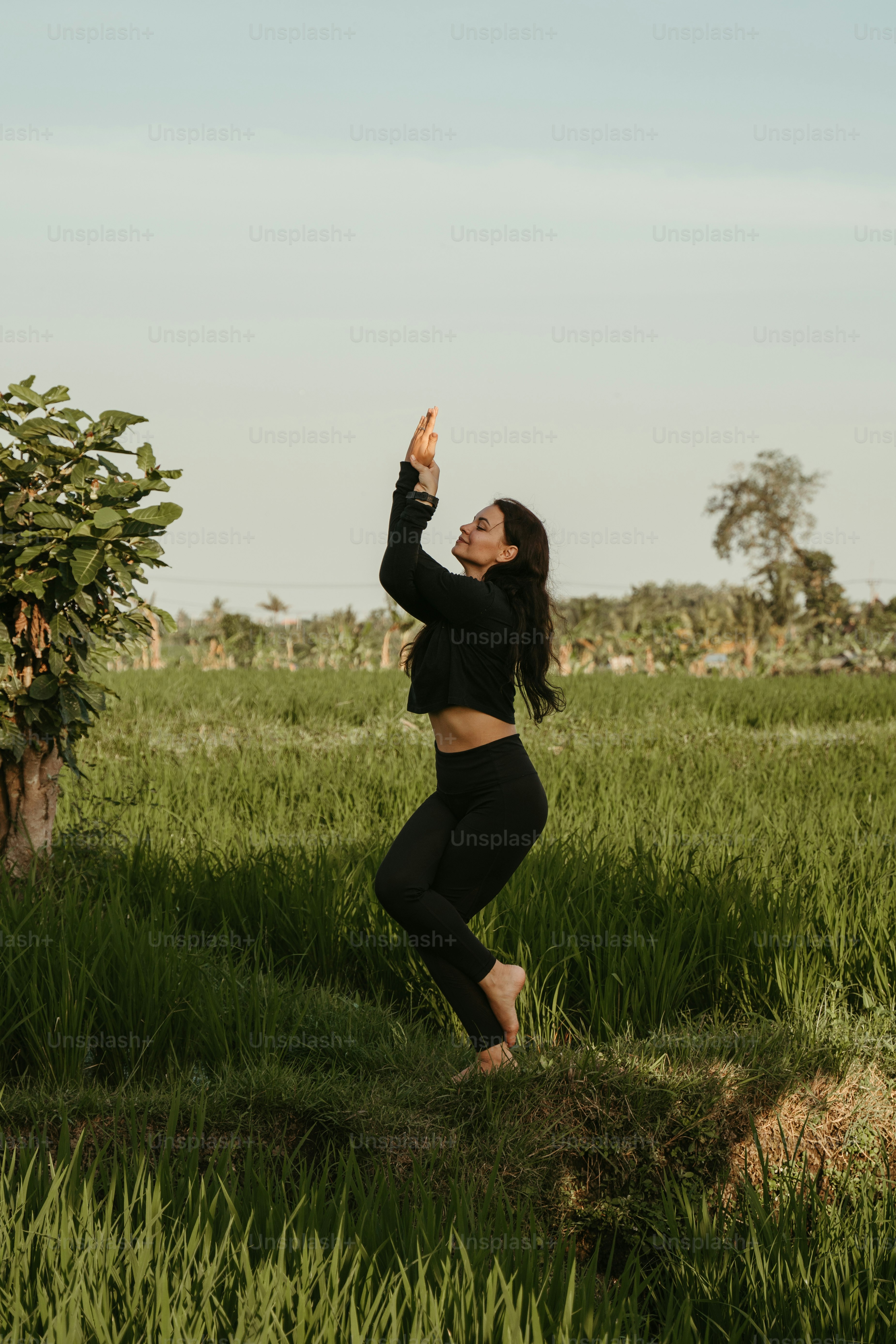 uma mulher em pé em um campo com os braços no ar