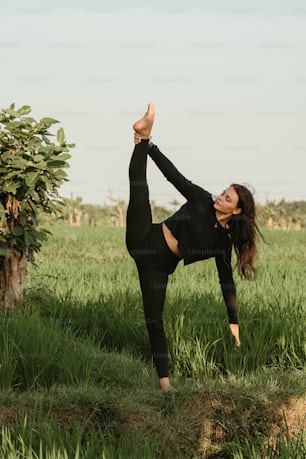 a woman doing a yoga pose in a field