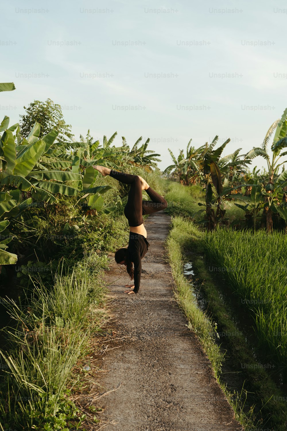 a woman is doing a handstand on a dirt road