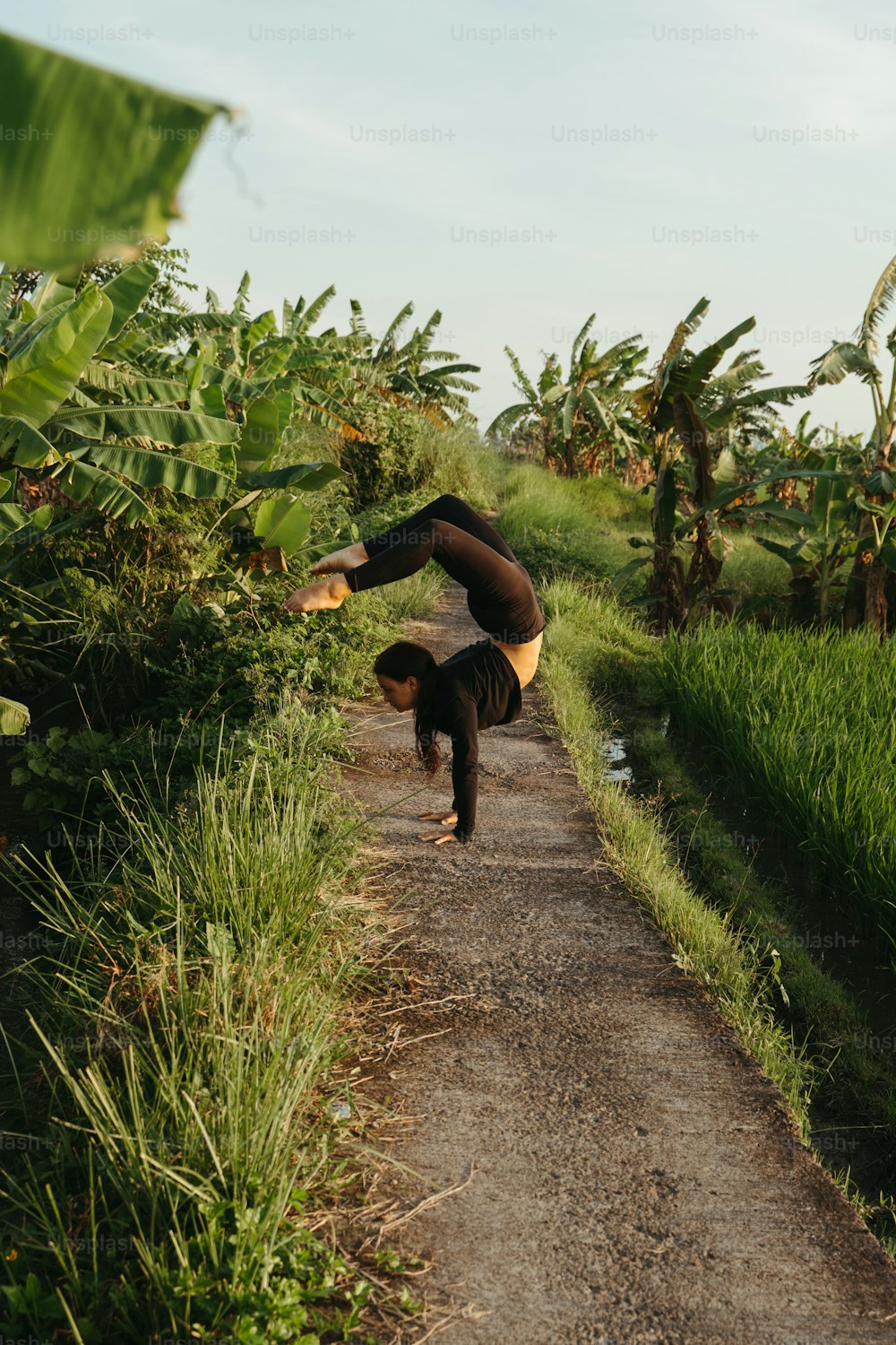 a person doing a handstand on a dirt road
