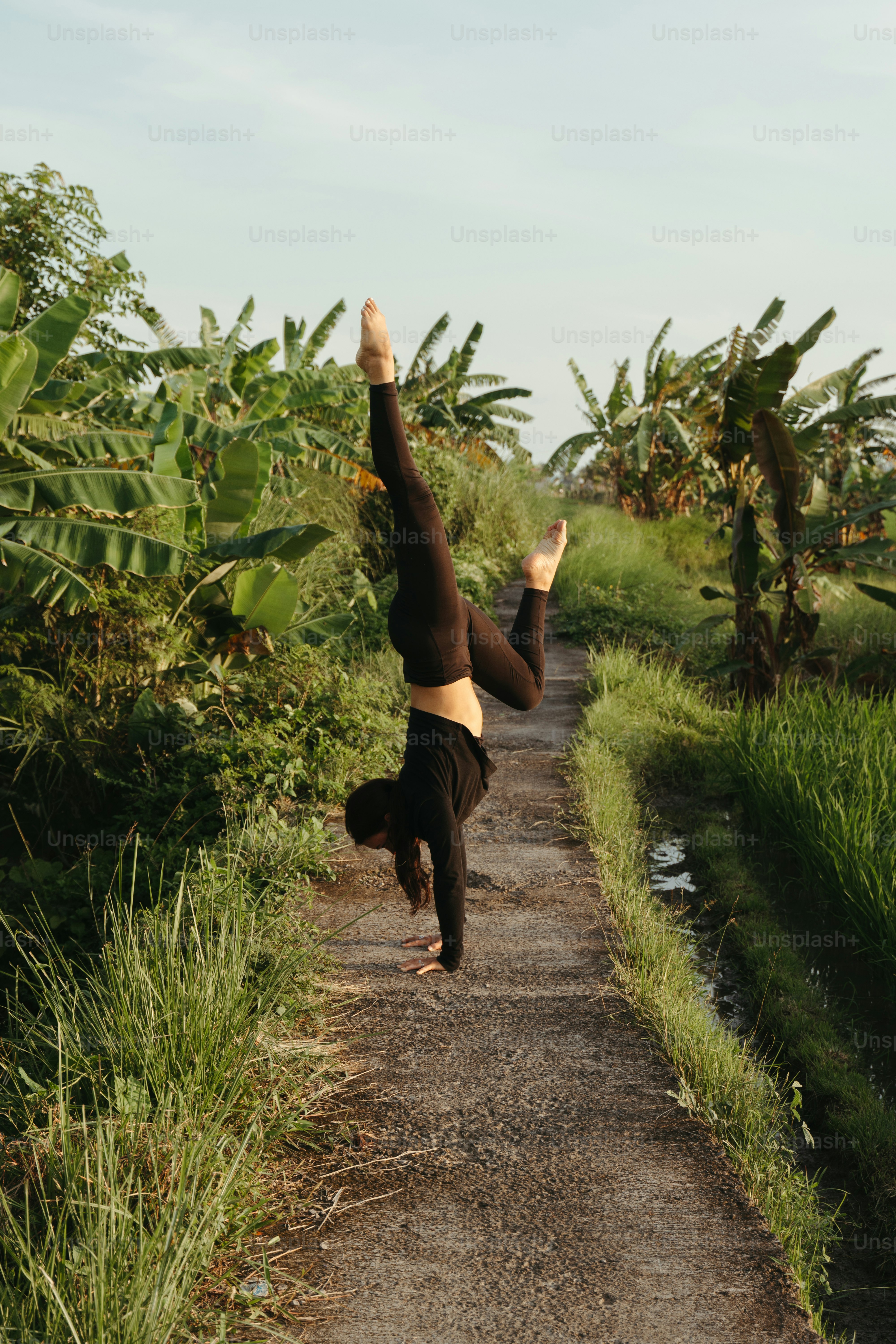 a person doing a handstand on a dirt road
