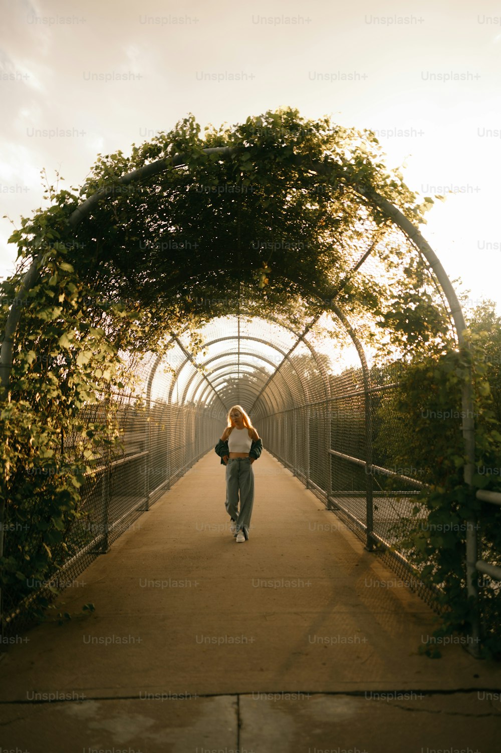 a woman walking down a walkway under a canopy