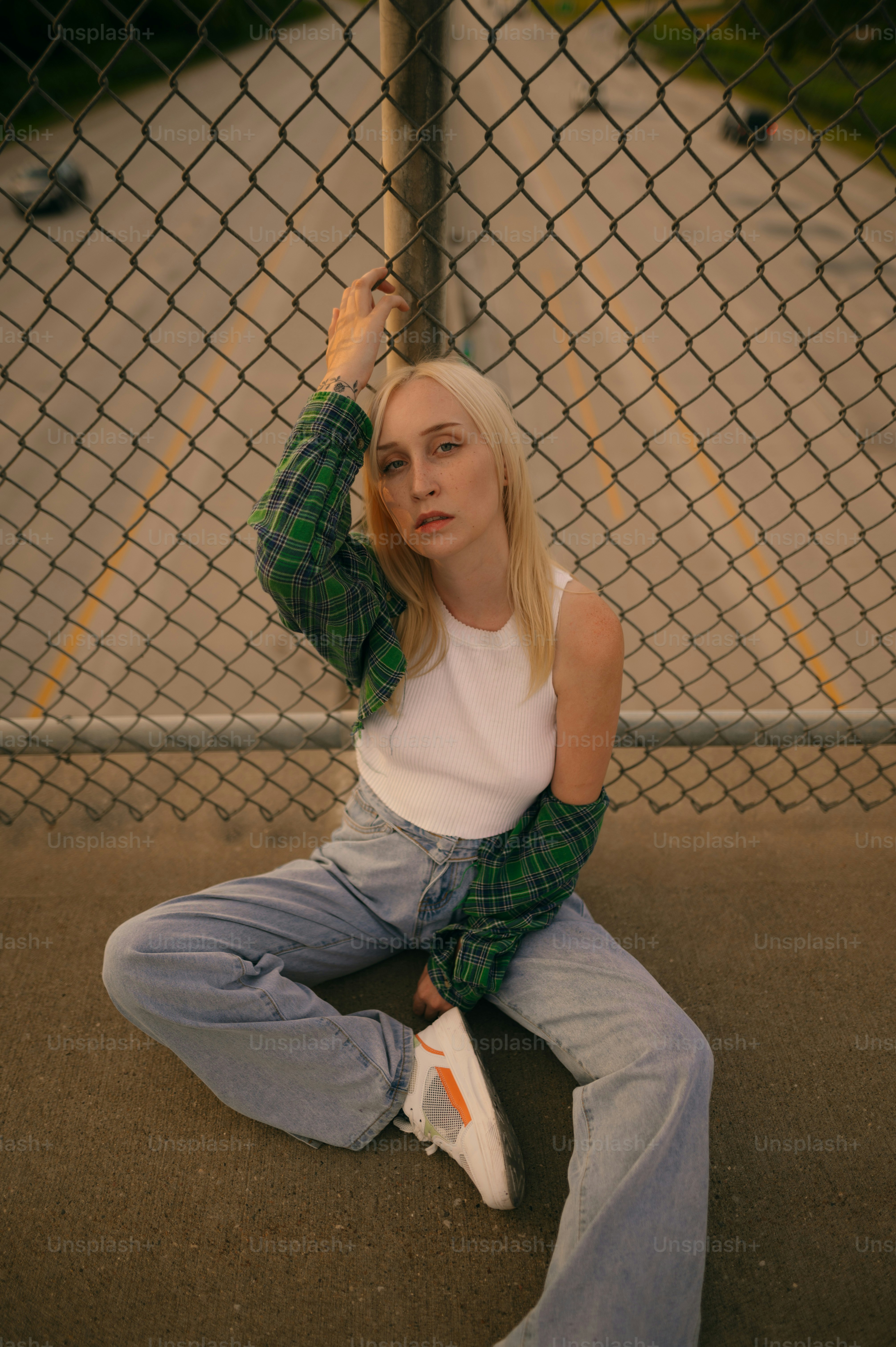 a woman sitting on the ground next to a fence