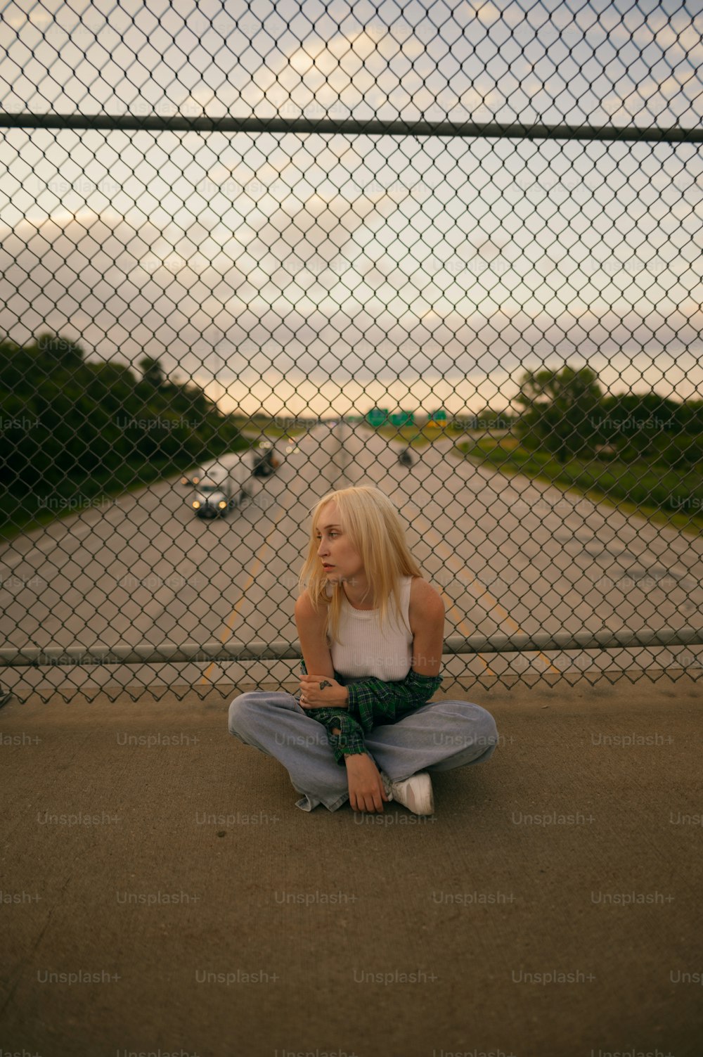 a woman sitting on the ground in front of a fence