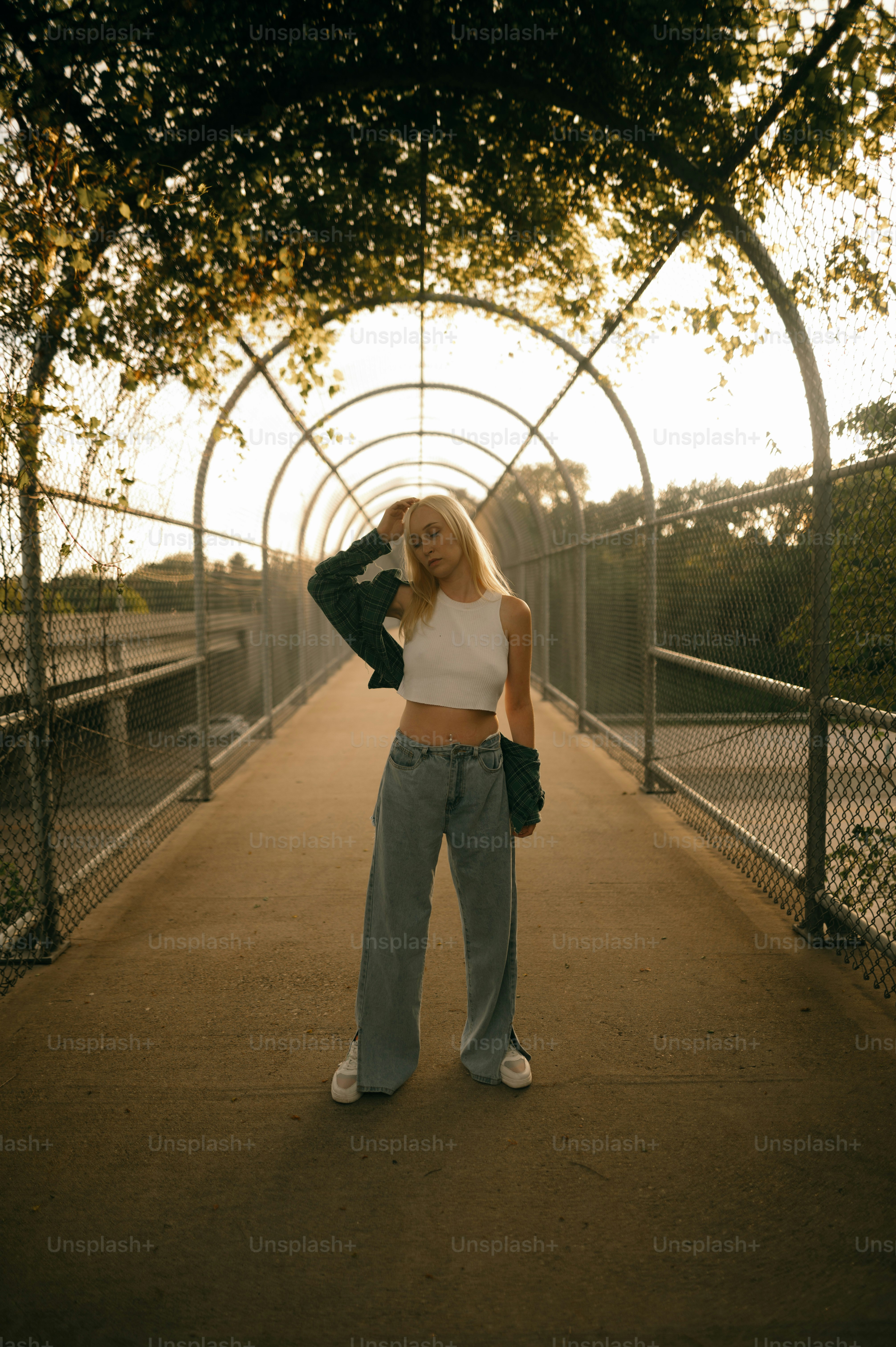 A woman standing on a bridge with her hands in her hair photo ...